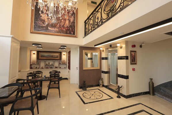 A spacious lobby with a high ceiling, a chandelier, a large painting, and a staircase. - Art Nouveau Pera (Istanbul)