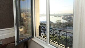 A room with a large window overlooking a cityscape, including a river and buildings. - Art Nouveau Pera (Istanbul)