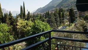 Un balcón con vistas a un paisaje montañoso, abundante vegetación y edificios a la distancia.