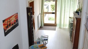 Un comedor con una mesa, sillas, una silla de oficina negra, una mesa de centro de vidrio y un tapete de diseño rojo y negro.