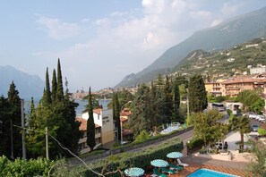 A coastal hotel with a pool, outdoor seating, and mountain views. - Hotel Stella Alpina (Malcesine)
