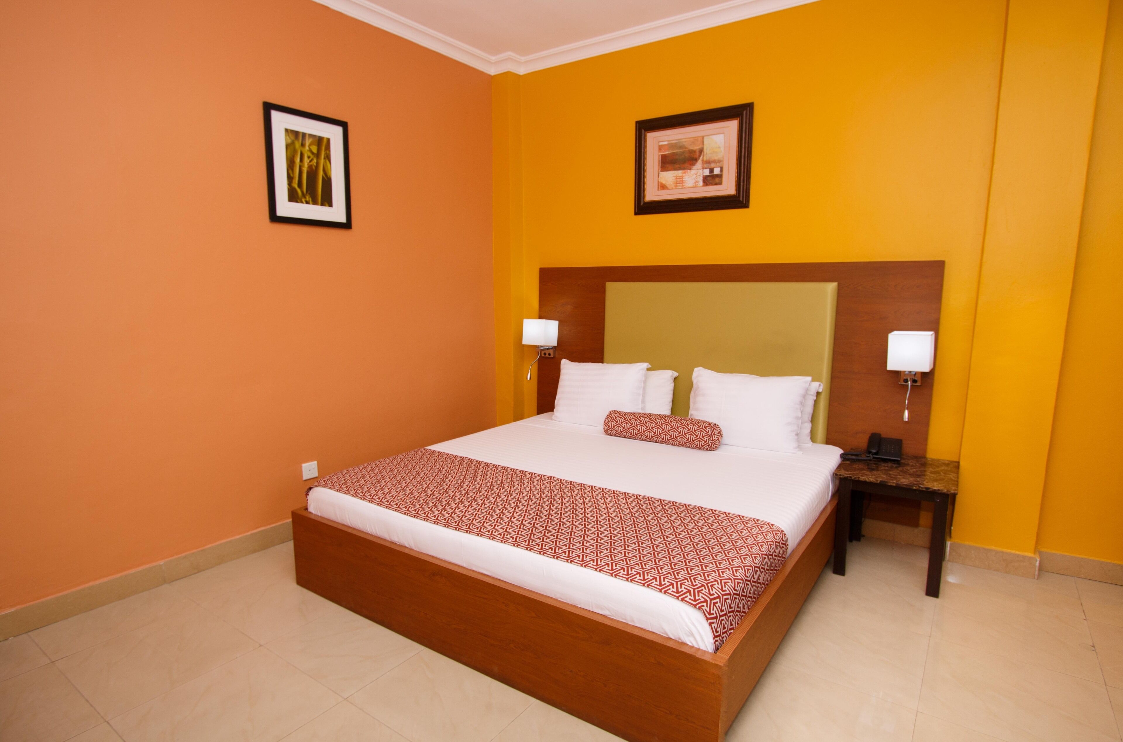 A hotel room with a large bed, two bedside tables, and two wall-mounted lamps.