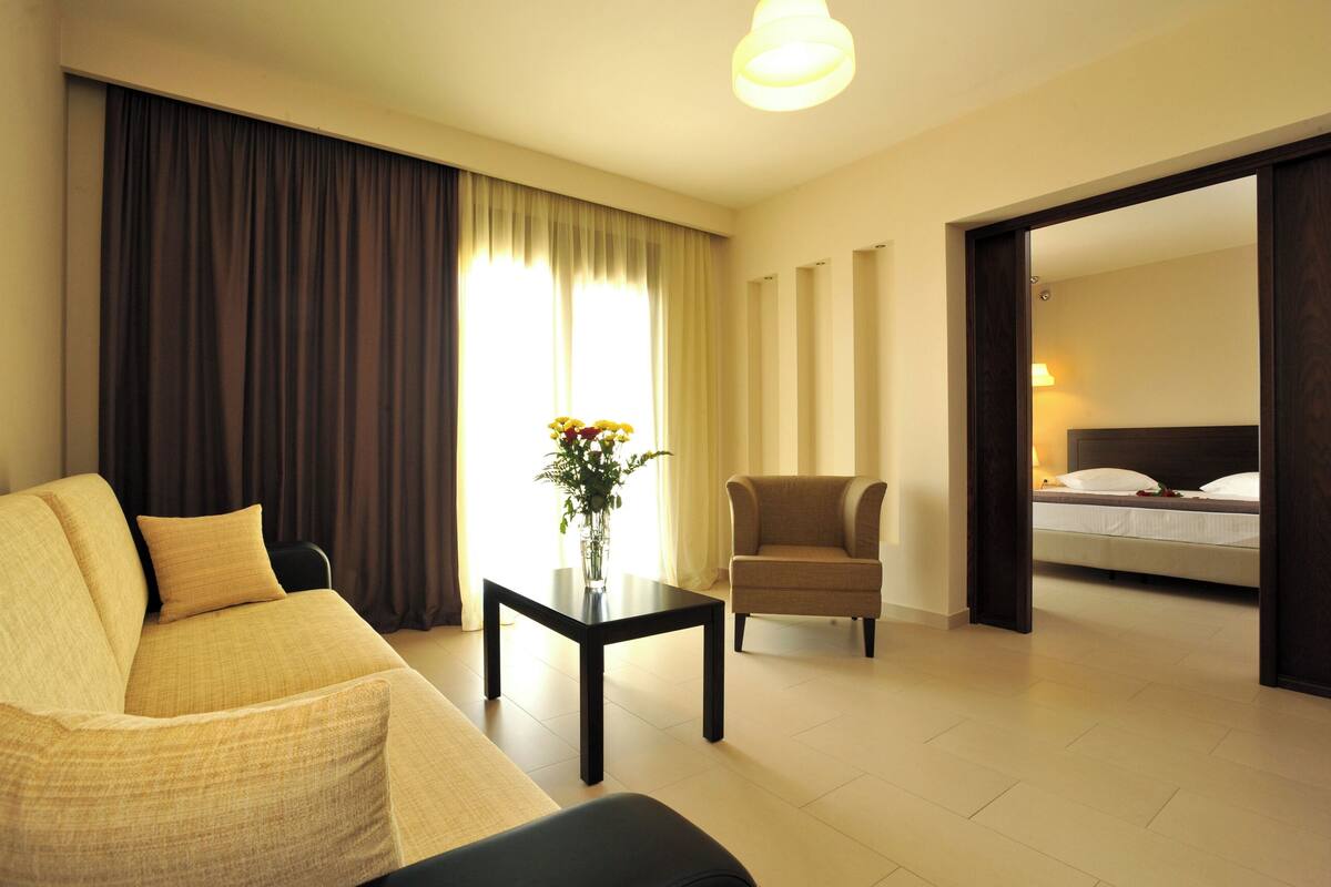 Ein Hotelzimmer mit Sofa, Sessel, kleinem Tisch und einem Bett.