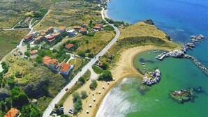 Eine Luftaufnahme einer Küstenstadt mit Strand, klarem blauen Meer und hügeliger Landschaft.