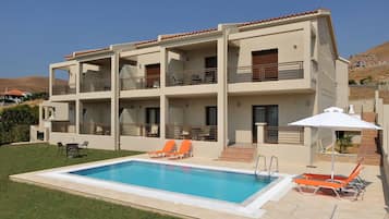 Una piscina al aire libre, sombrillas, sillones reclinables de piscina