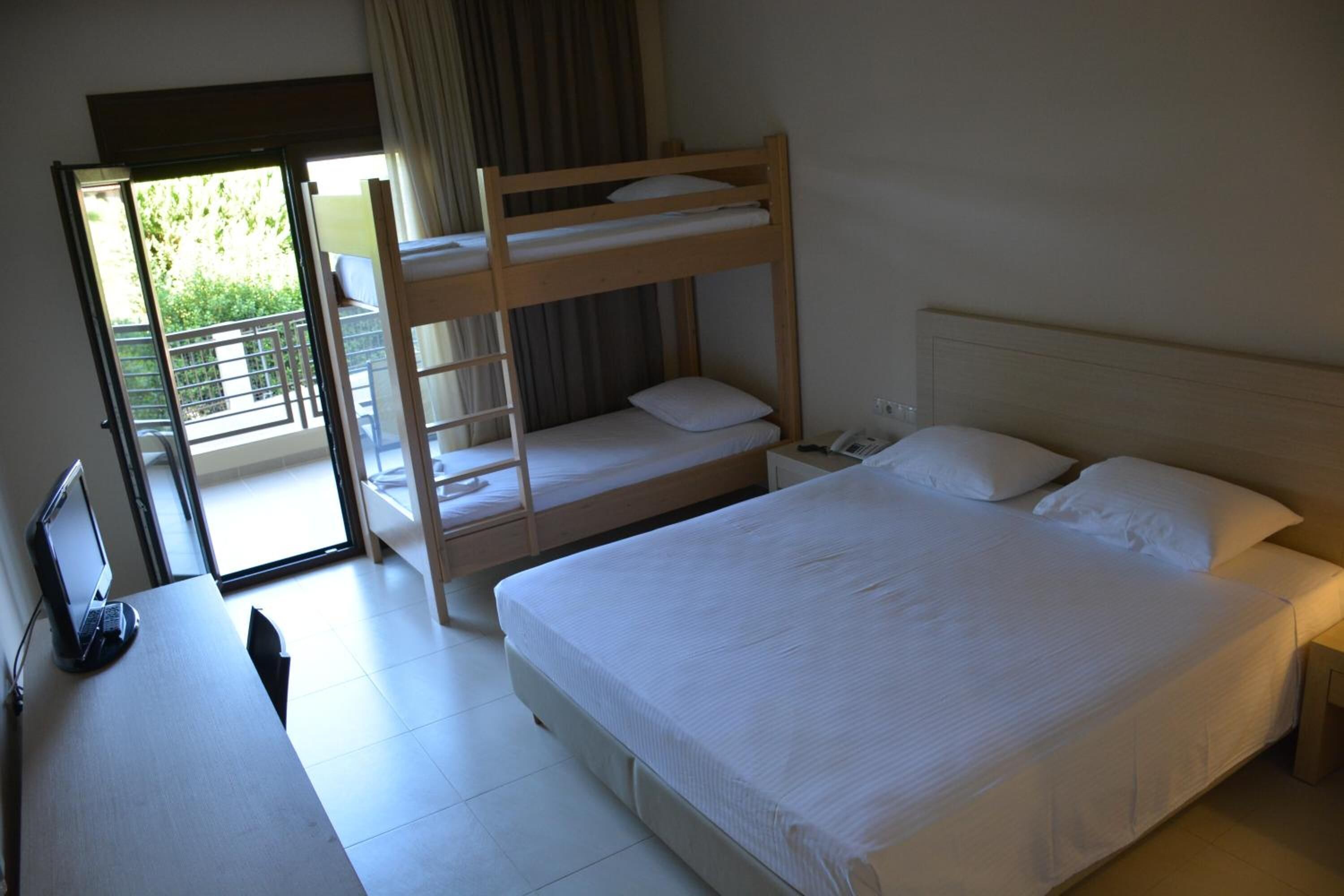 Une chambre d’hôtel avec un lit superposé, un bureau avec un ordinateur portable et un grand lit.