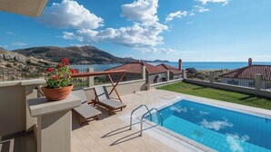 Ein Poolbereich mit Liegestühlen und Meerblick.