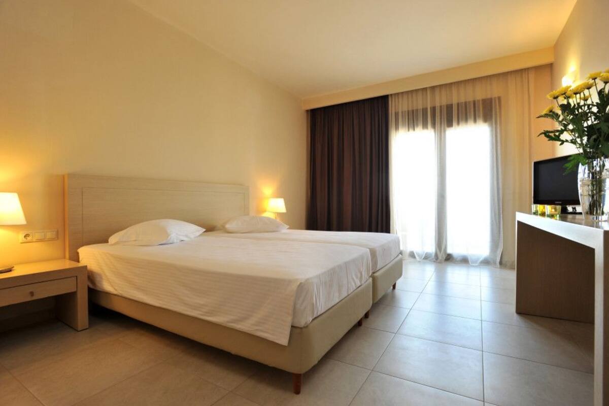 Ein Hotelzimmer mit einem Doppelbett, Nachttischen, einem Schreibtisch mit Stuhl und einem Fernseher.