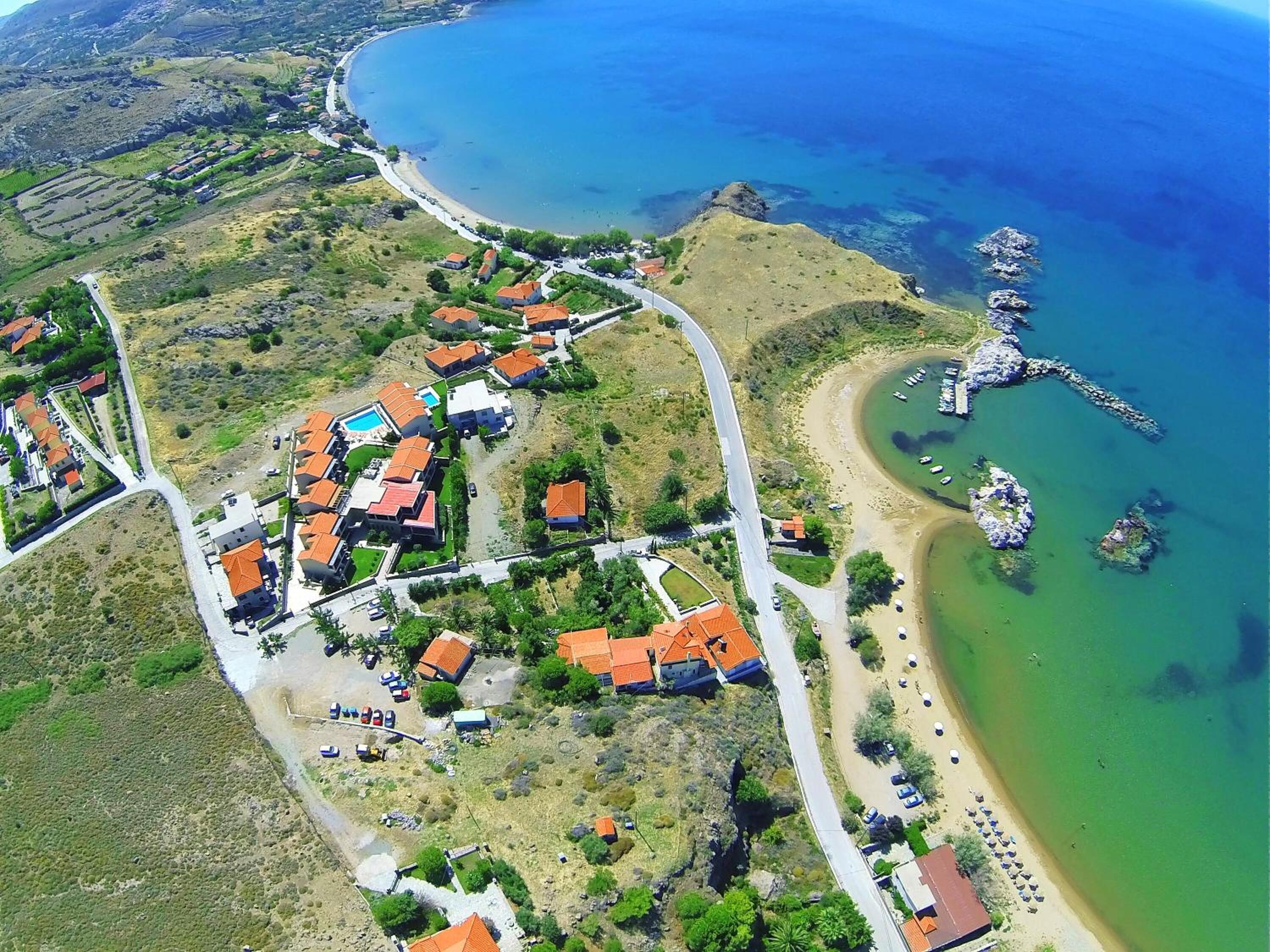 An aerial view of a coastal village with houses, a beach, and boats.