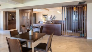 Ein geräumiger Speiseraum mit einem langen Tisch und mehreren Stühlen, ein Empfangsbereich mit einer Holzwand und einem modernen Interieur.