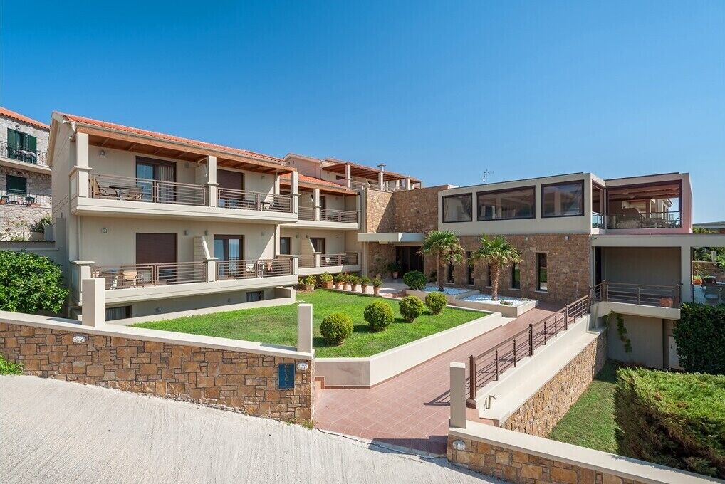 A modern multi-story residential building with balconies, a courtyard, and stone walls.
