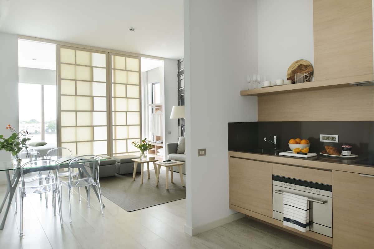 A modern kitchen with a dining area, large windows, and a built-in oven.