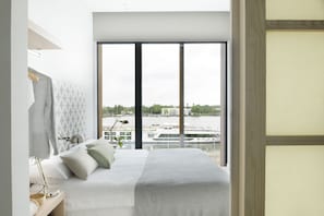 A modern hotel room with a large window offering a view of a river and buildings. - Eric Vökel Boutique Apartments Amsterdam Suites (Amsterdam)