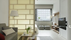 A modern living room with a sofa, a coffee table, a lamp, and a TV.
