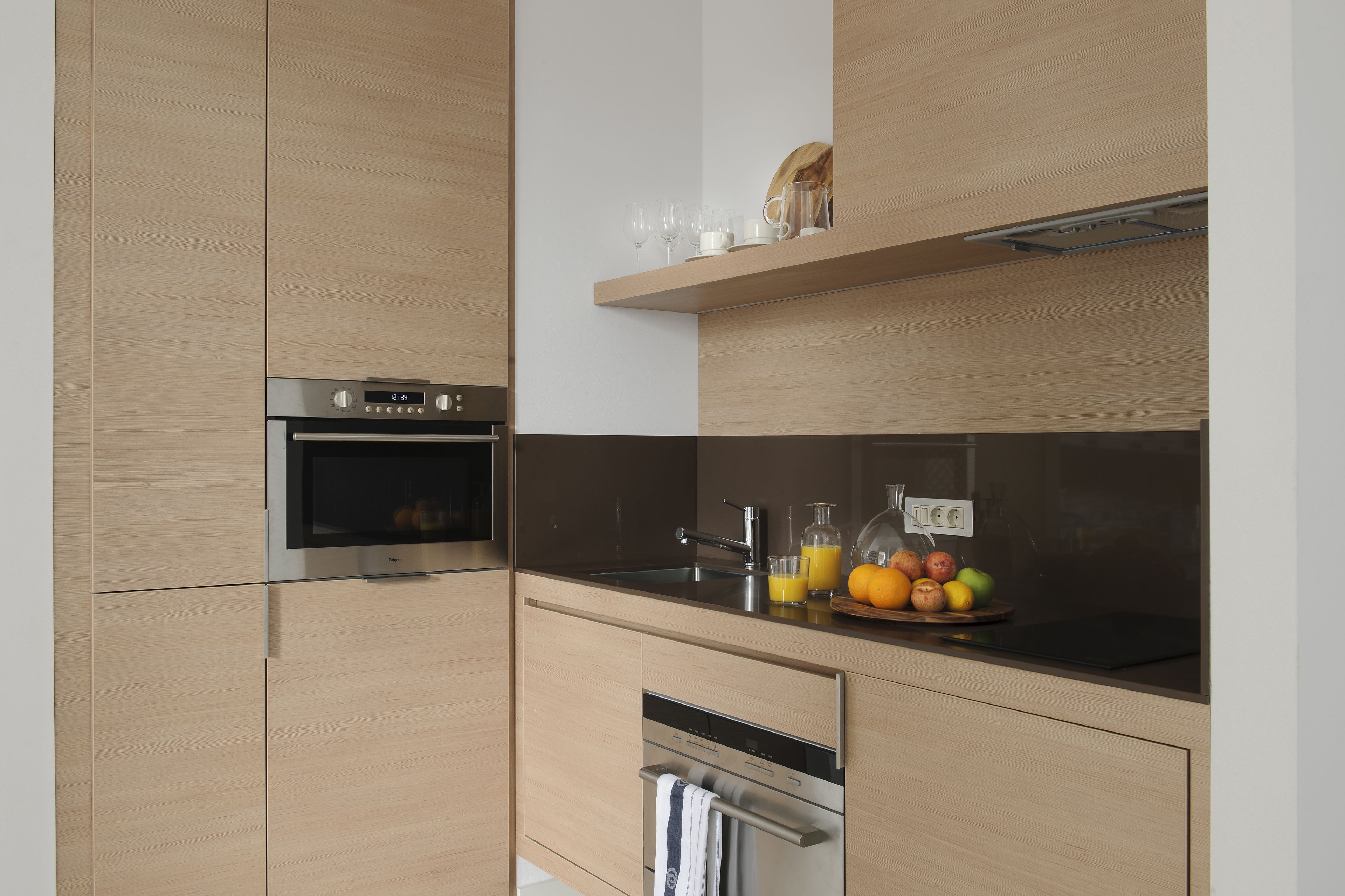 A modern kitchen with wooden cabinets, stainless steel appliances, and a fruit bowl on the counter.