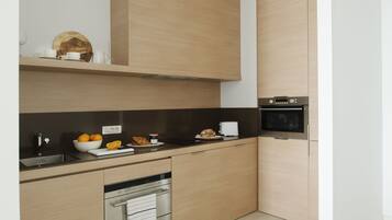 Una cocina moderna con armarios de madera clara, encimera negra y electrodomésticos de acero inoxidable.
