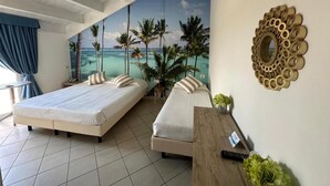 A hotel room with two beds, a view of a beach, and a decorative mirror. - Hotel Liberty Beach (Riccione)