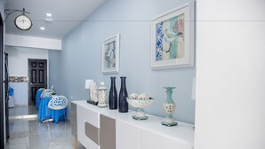 A hallway with a white reception desk, framed artwork, and a clock. - Hotel Portal de San Antonio (Cartagena)