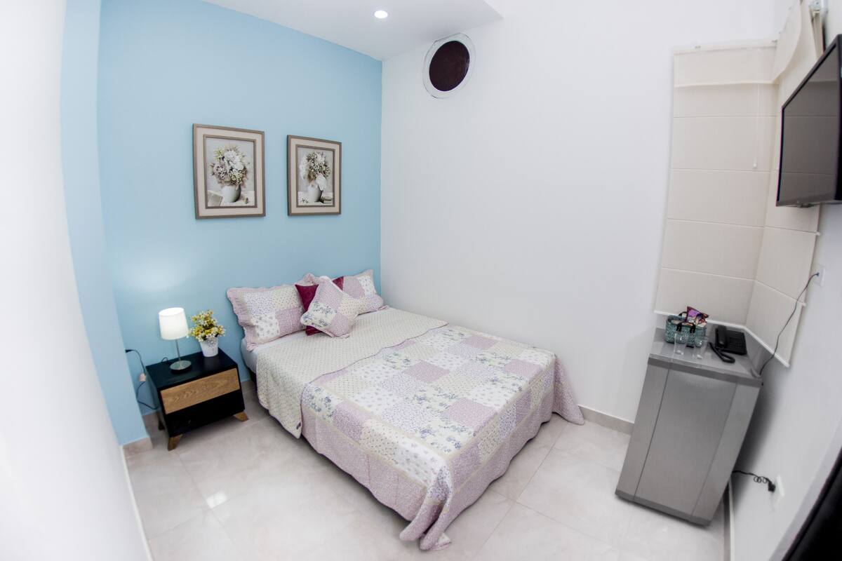 A bedroom with a bed, nightstand, and a small cabinet.