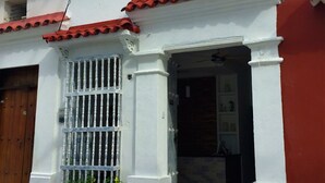 A two-story building with a red-tiled roof and white walls. - Hotel Portal de San Antonio (Cartagena)