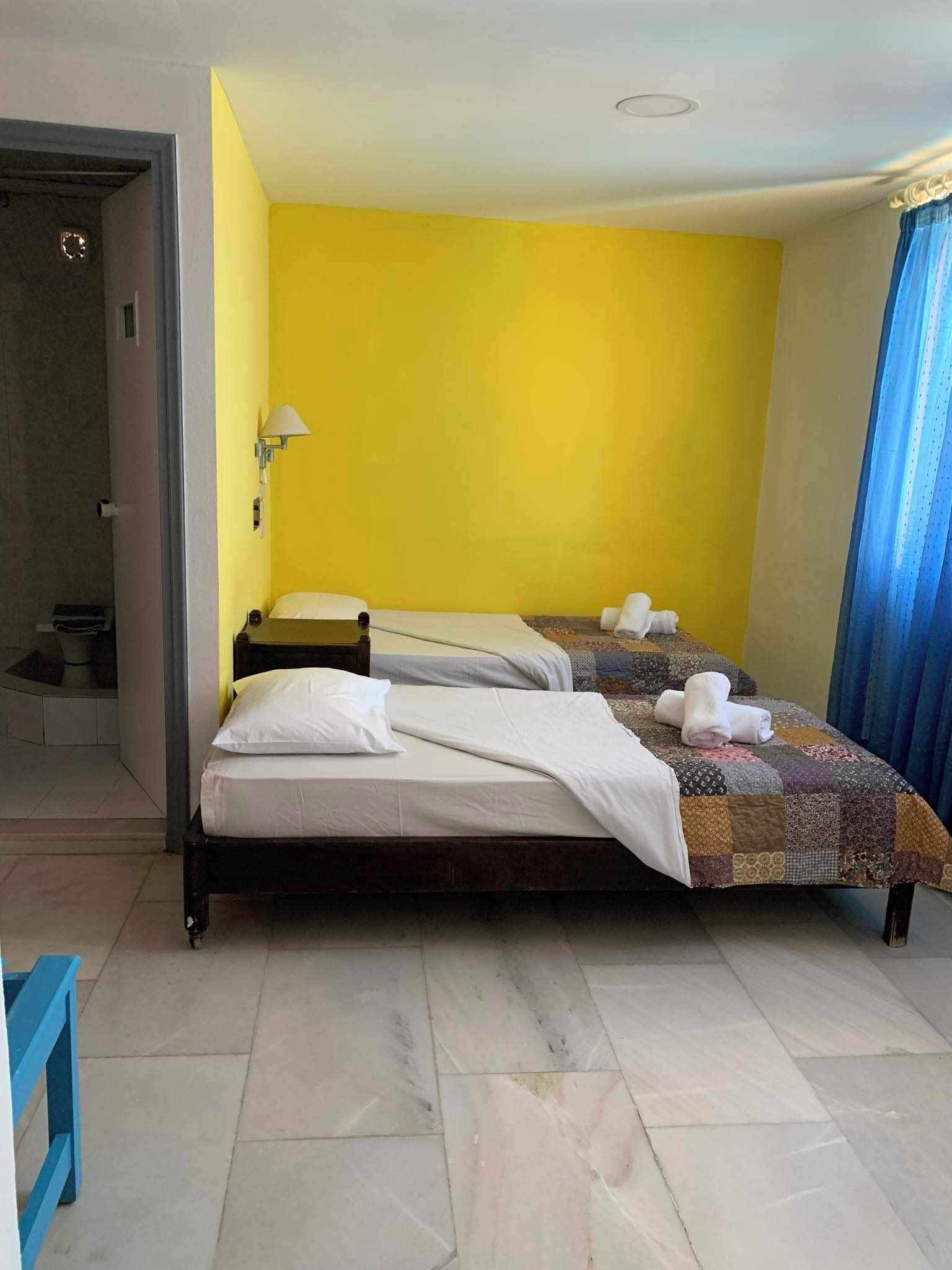 A hotel room with two beds, a bathroom, and a view of the street.