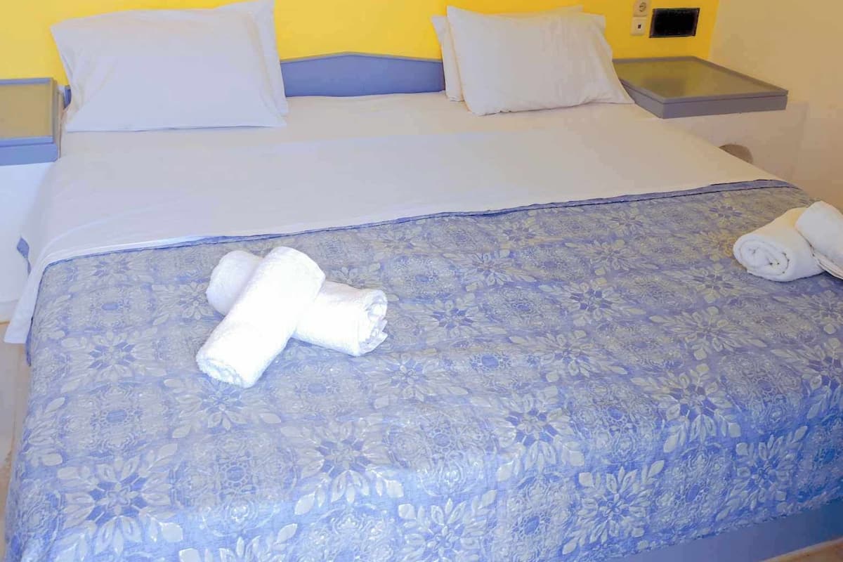 A hotel room with a bed, two bedside tables, and two wall-mounted lamps.