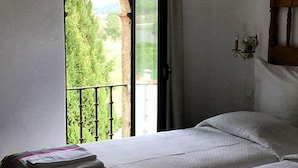 A bedroom with a bed, a window with a view of greenery, and a wall-mounted light fixture. - Herdade da Maxuqueira (Gaviao)