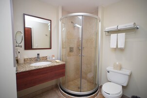 A bathroom with a glass-enclosed shower, a sink with a wooden vanity, and a toilet.