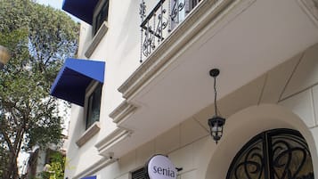 Un edificio con un letrero que dice “Senia” y una reja de hierro forjado negro.