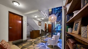 A modern interior with a geometric patterned floor, a staircase, a reception desk, and a seating area with a unique hanging light fixture. - Senia Reforma (Mexico City)