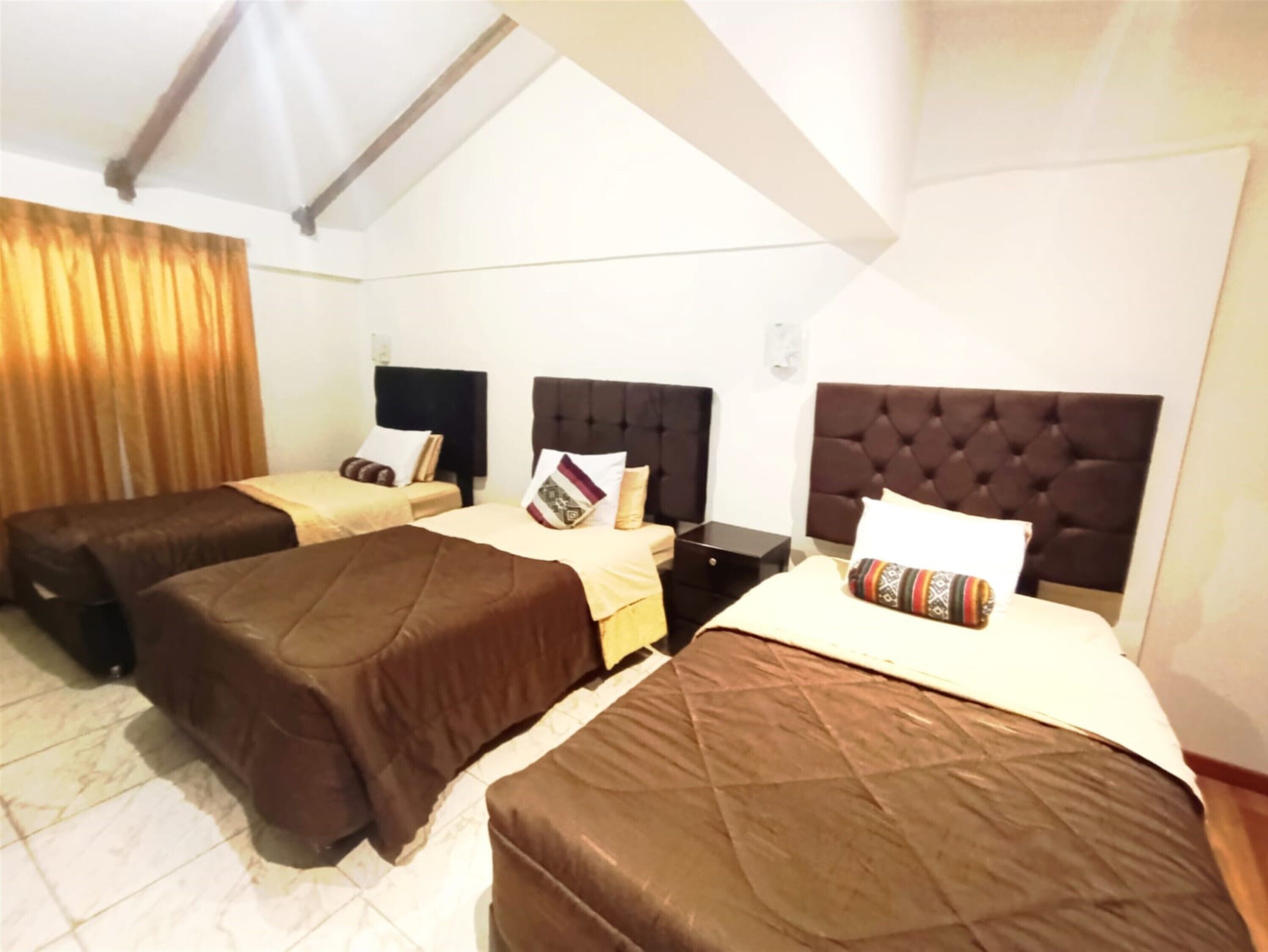 A hotel room with two single beds, a nightstand, and a large window with curtains.