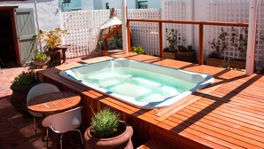 A wooden deck with a hot tub, outdoor seating, and potted plants. - Paternoster Manor (Paternoster)