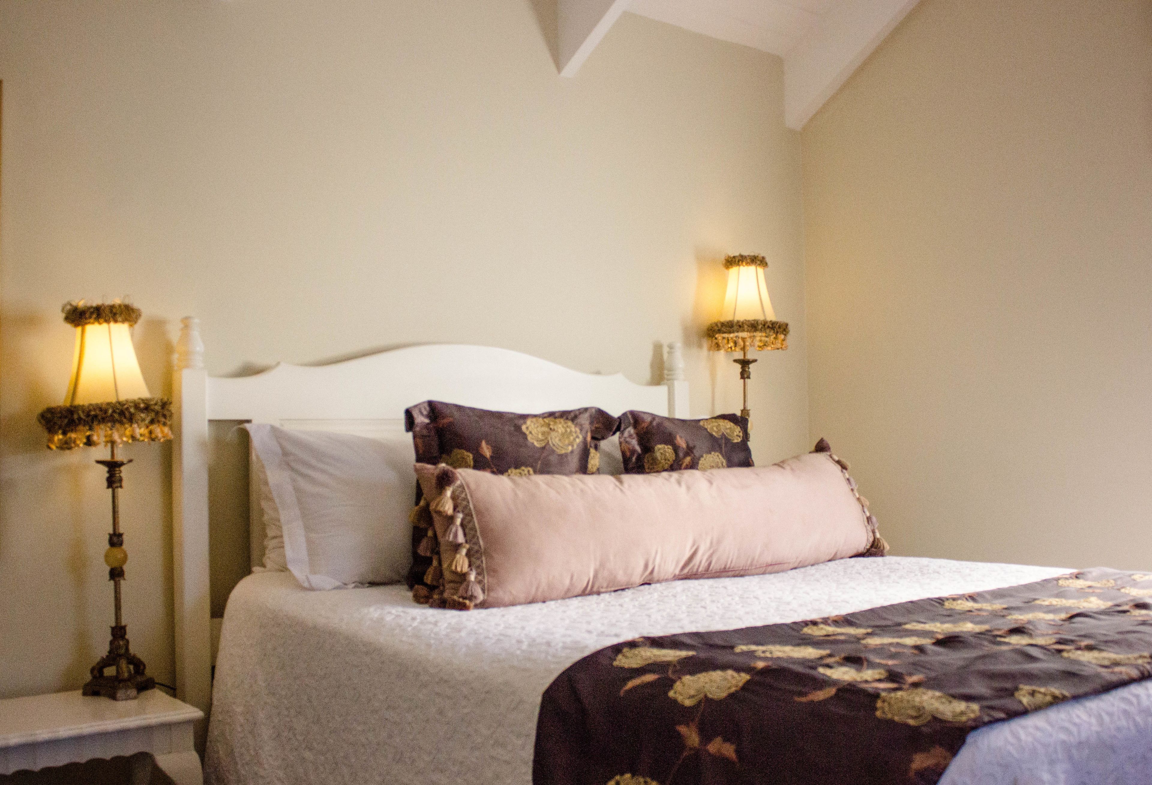 A neatly made bed with a white headboard, two bedside lamps, and a floral-patterned bedspread.