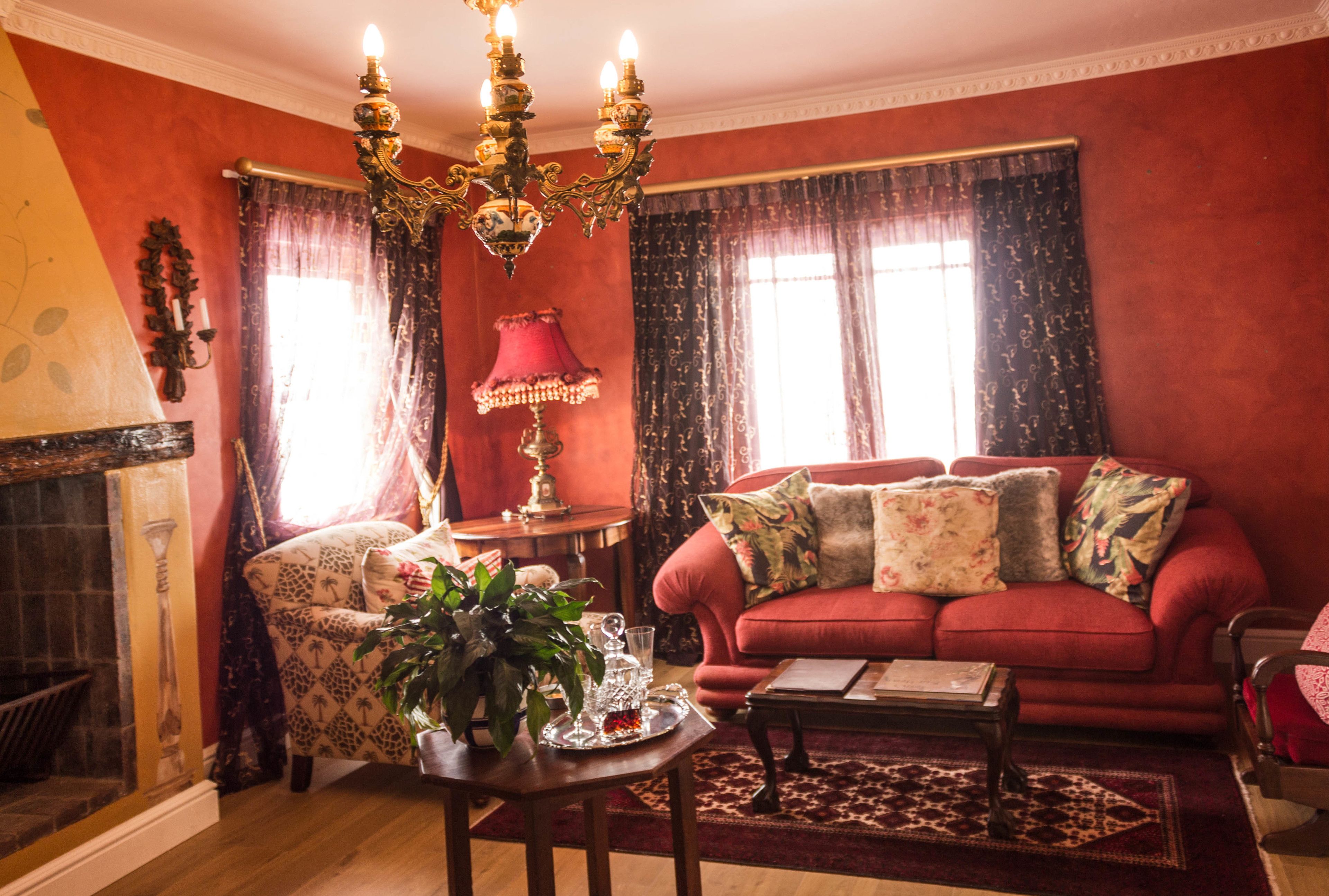 A room with a red sofa, a patterned armchair, a wooden coffee table, and a chandelier.