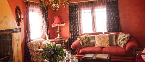 A room with a red sofa, a patterned armchair, a wooden coffee table, and a chandelier.