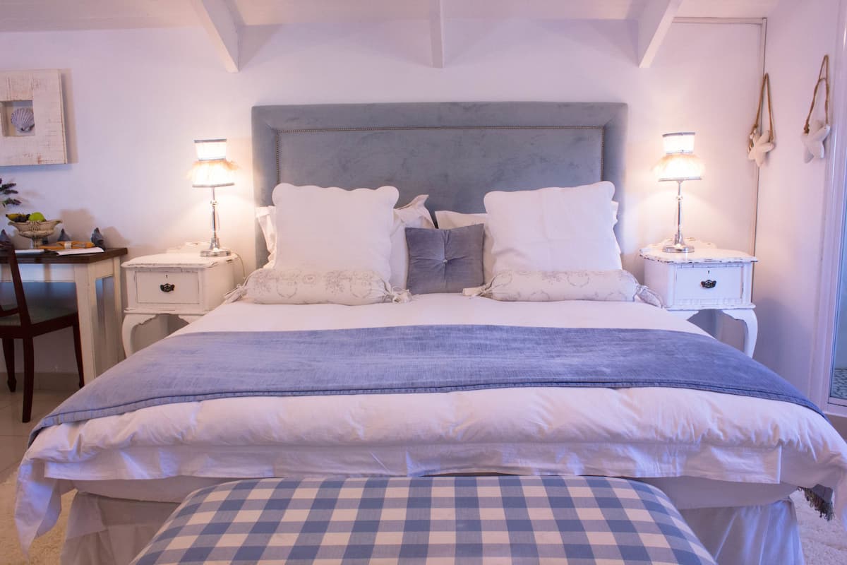 A bedroom with a large bed, two bedside tables, a chair, and a desk.
