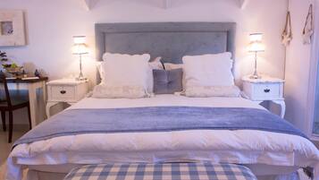 Un dormitorio con una cama grande, dos mesitas de noche, una silla y un escritorio.