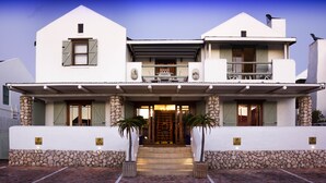 A two-story building with a stone foundation, a balcony, and a front door with steps leading up to it. - Paternoster Manor (Paternoster)