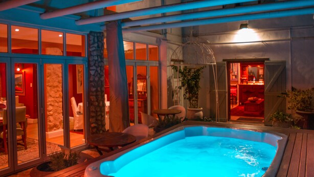 A hot tub area with a pool, stone pillar, and glass doors leading to a dining area. - Paternoster Manor (Paternoster)