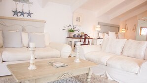 A cozy, well-lit living room with a white sofa set, a wooden coffee table, and a decorative wall hanging. - Paternoster Manor (Paternoster)