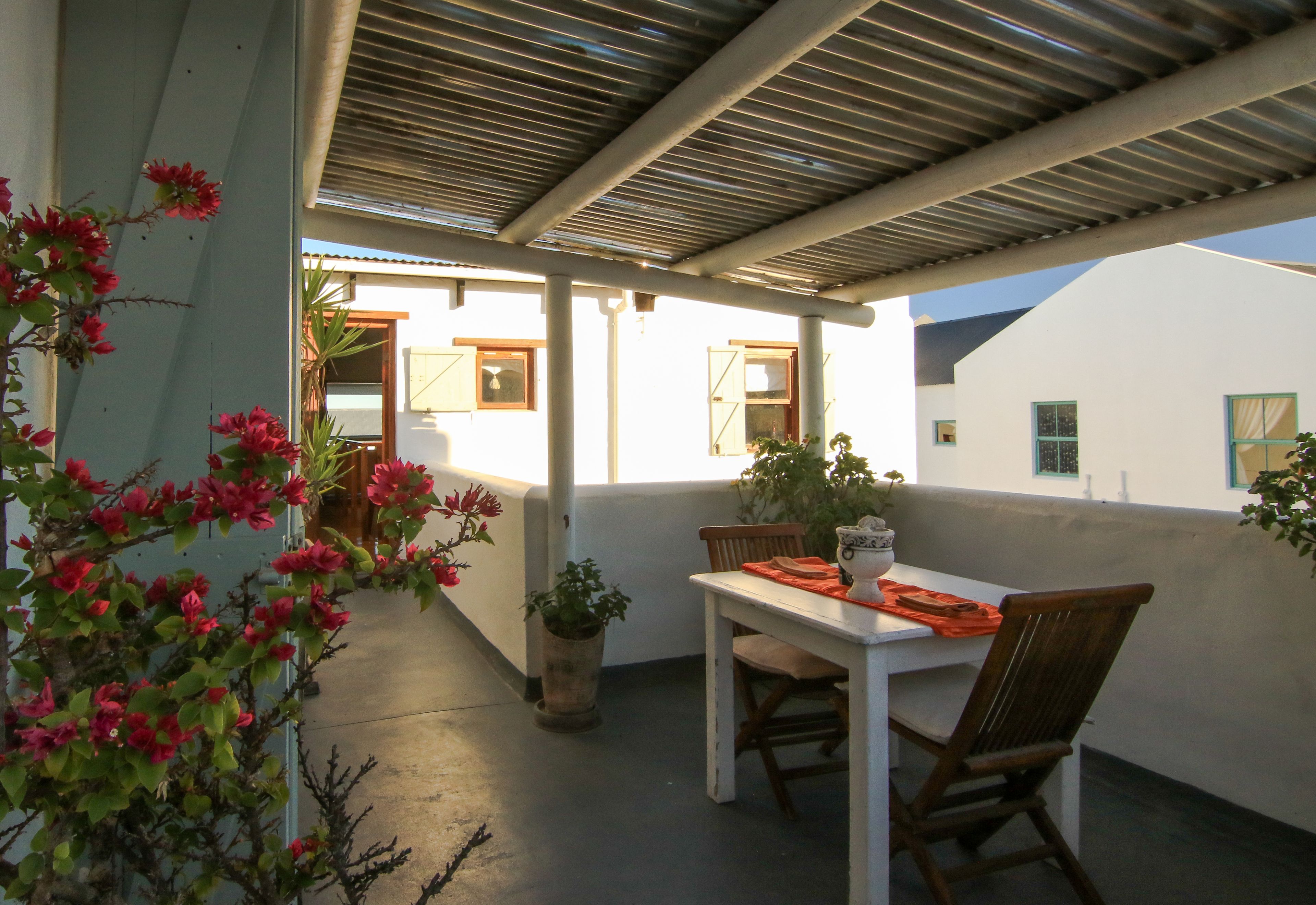 Un patio al aire libre con una mesa, sillas, una planta en maceta y vistas de los edificios circundantes.