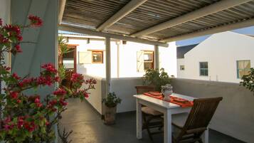 Un patio al aire libre con una mesa, sillas, una planta en maceta y vistas de los edificios circundantes.