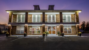 A two-story building with a brick facade, large windows, and a parking lot in front. - Richland Inn Lawrenceburg (Lawrenceburg)