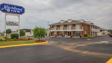 A Richland Inn hotel with a signboard, a parking lot, and a brick building with a balcony.