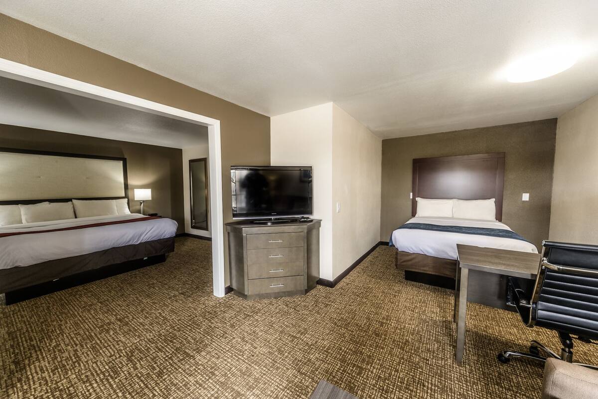 A hotel room with two beds, a TV, a desk, and a chair.
