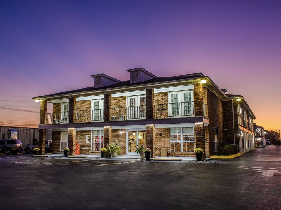 A two-story building with a brick facade, large windows, and a flat roof.