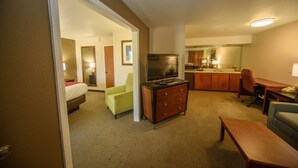 A hotel room with a bed, a TV, a desk, a chair, and a kitchenette. - Richland Inn Lawrenceburg (Lawrenceburg)