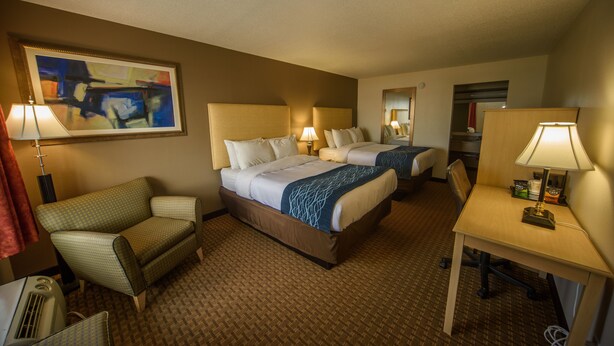 A hotel room with two beds, a desk, a chair, and a painting on the wall. - Richland Inn Lawrenceburg (Lawrenceburg)