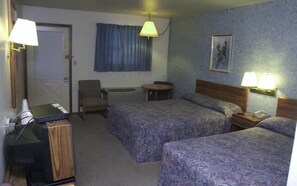 A hotel room with two beds, a desk, a chair, a small table, and a ceiling fan. - Quik Stop and Motel (Wausaukee)