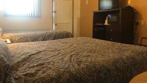 A hotel room with two beds, a television on a cabinet, and a door. - Quik Stop and Motel (Wausaukee)